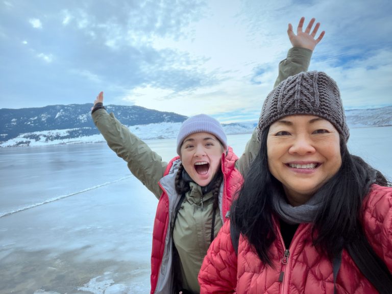 Asian mother and daughter at frozen lakeside in winter