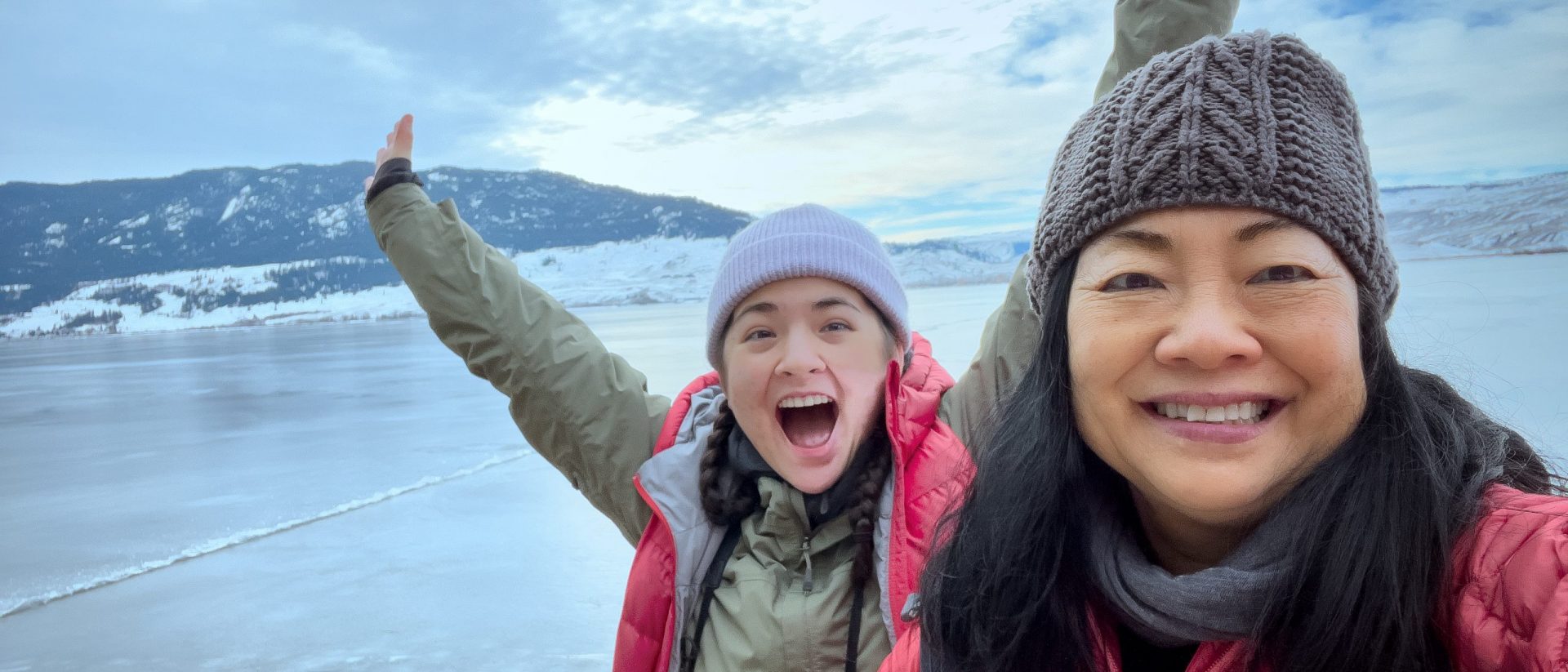 Asian mother and daughter at frozen lakeside in winter