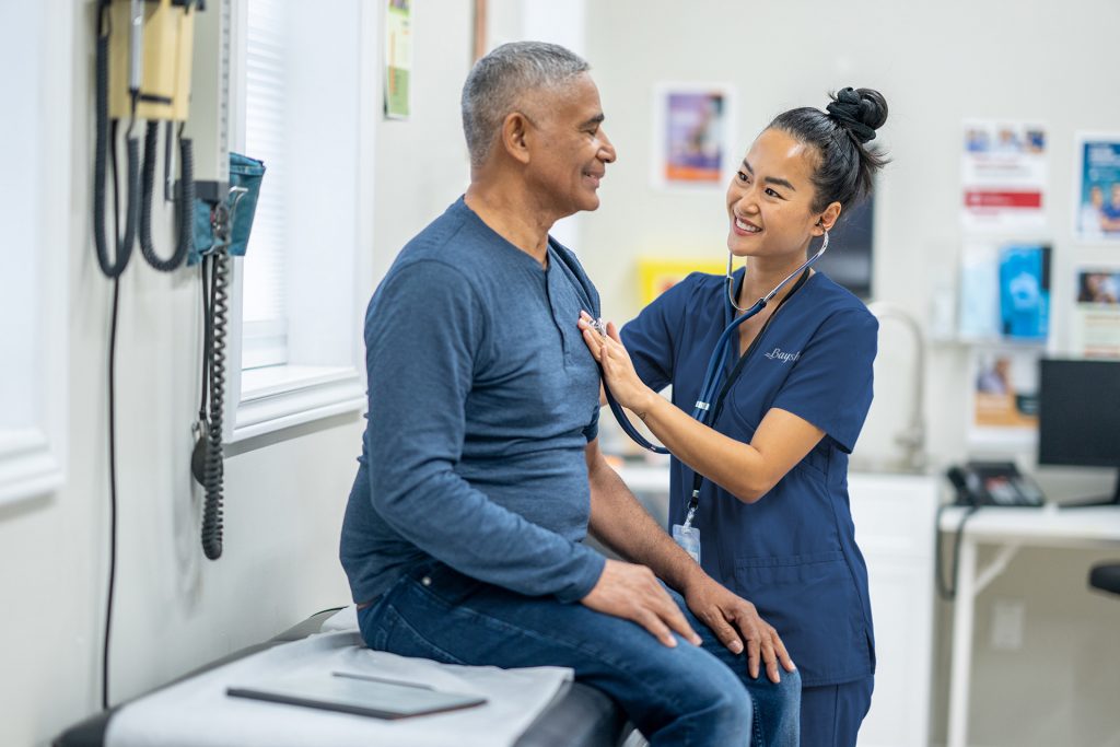 A nurse listens to a man's heart using a stethoscope