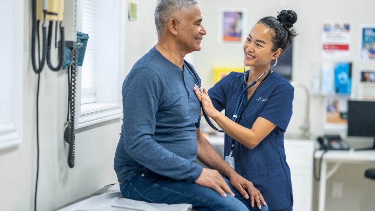 A nurse listens to a man's heart using a stethoscope