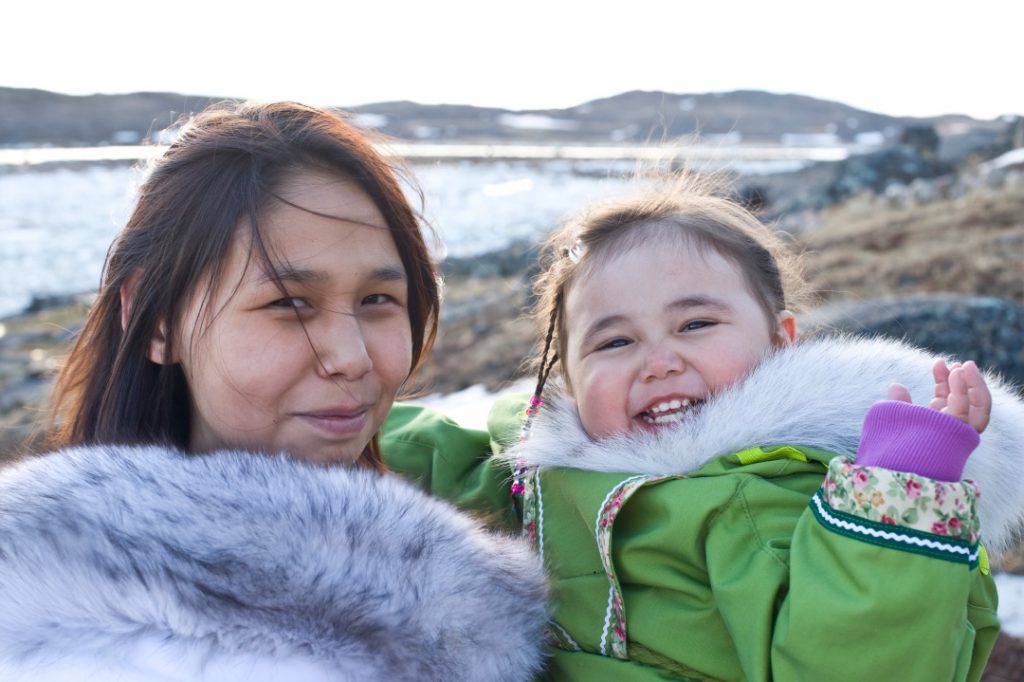 Une femme autochtone et un enfant souriant à la caméra